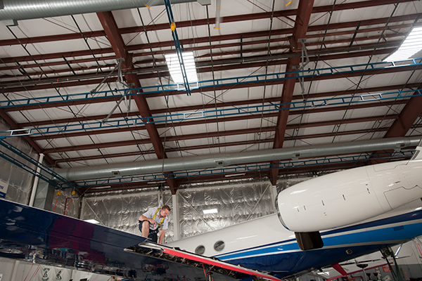 man working on airplane attached to traveling bridge