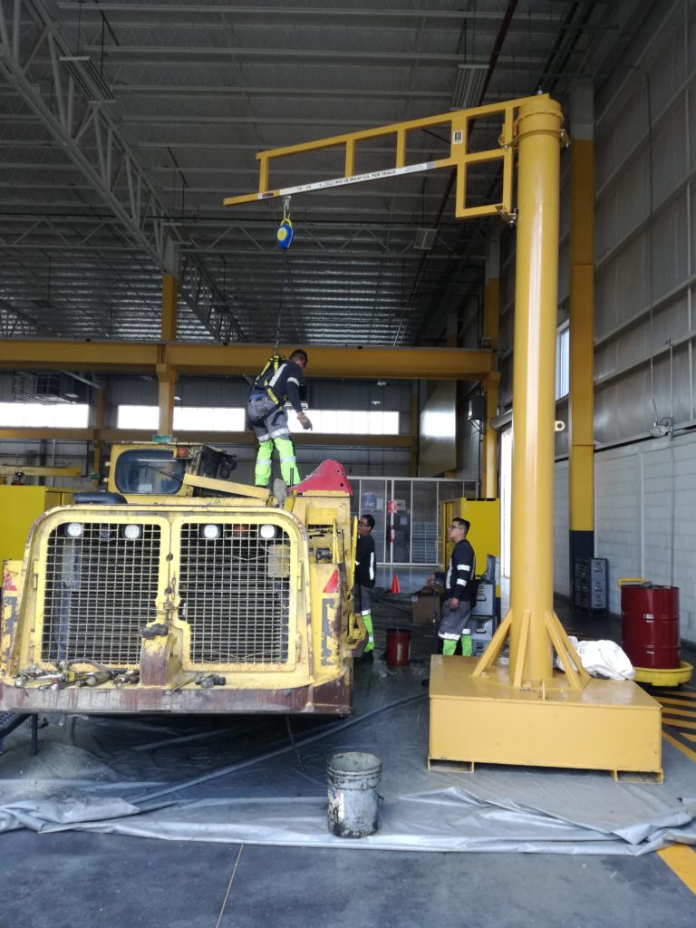 man working on a large vehicle in harness anchored to tracks