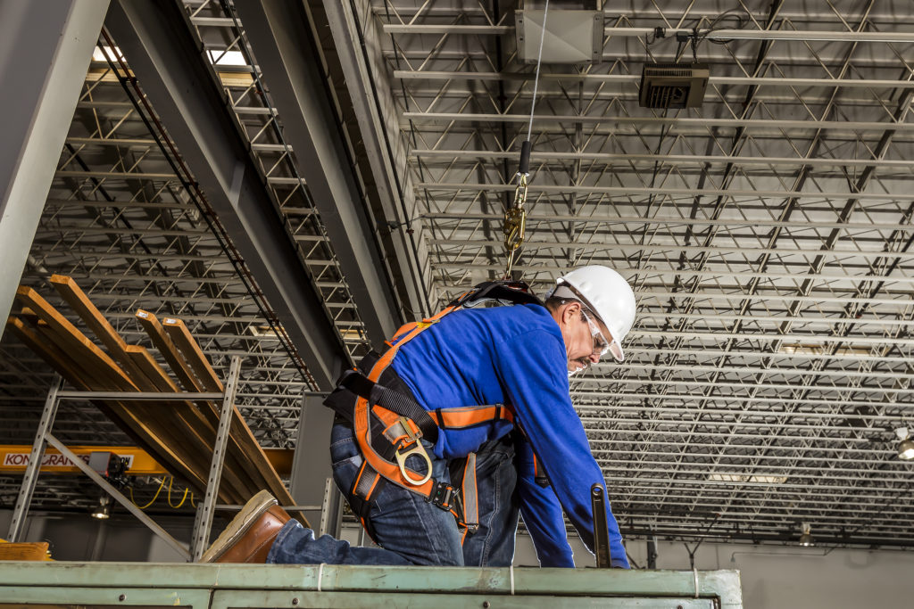 man wearing orange safety harness while working
