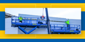 Two workers standing on two different scissor lifts install siding on a warehouse building